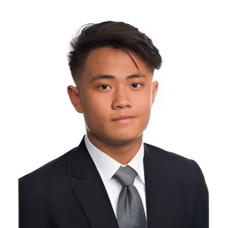 Man wearing a dark suit and gray tie against a white background